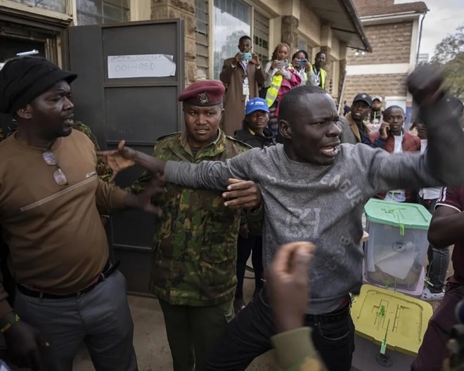 People argue with others from different parties and security forces trying to keep order, after a few ballot boxes were discovered with their seals broken, at a tallying center in the Mathare area of Nairobi, Kenya Wednesday, Aug. 10, 2022. Kenyans are waiting for the results of a close presidential election in which the turnout was lower than usual.  BEN CURTIS / AP PHOTO